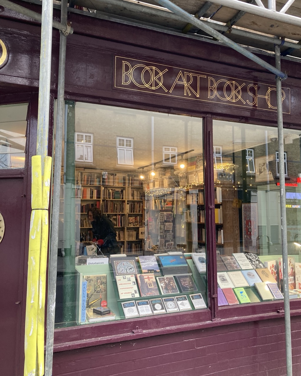 Photograph looking into a bookshop, with purple walls and scaffolding.