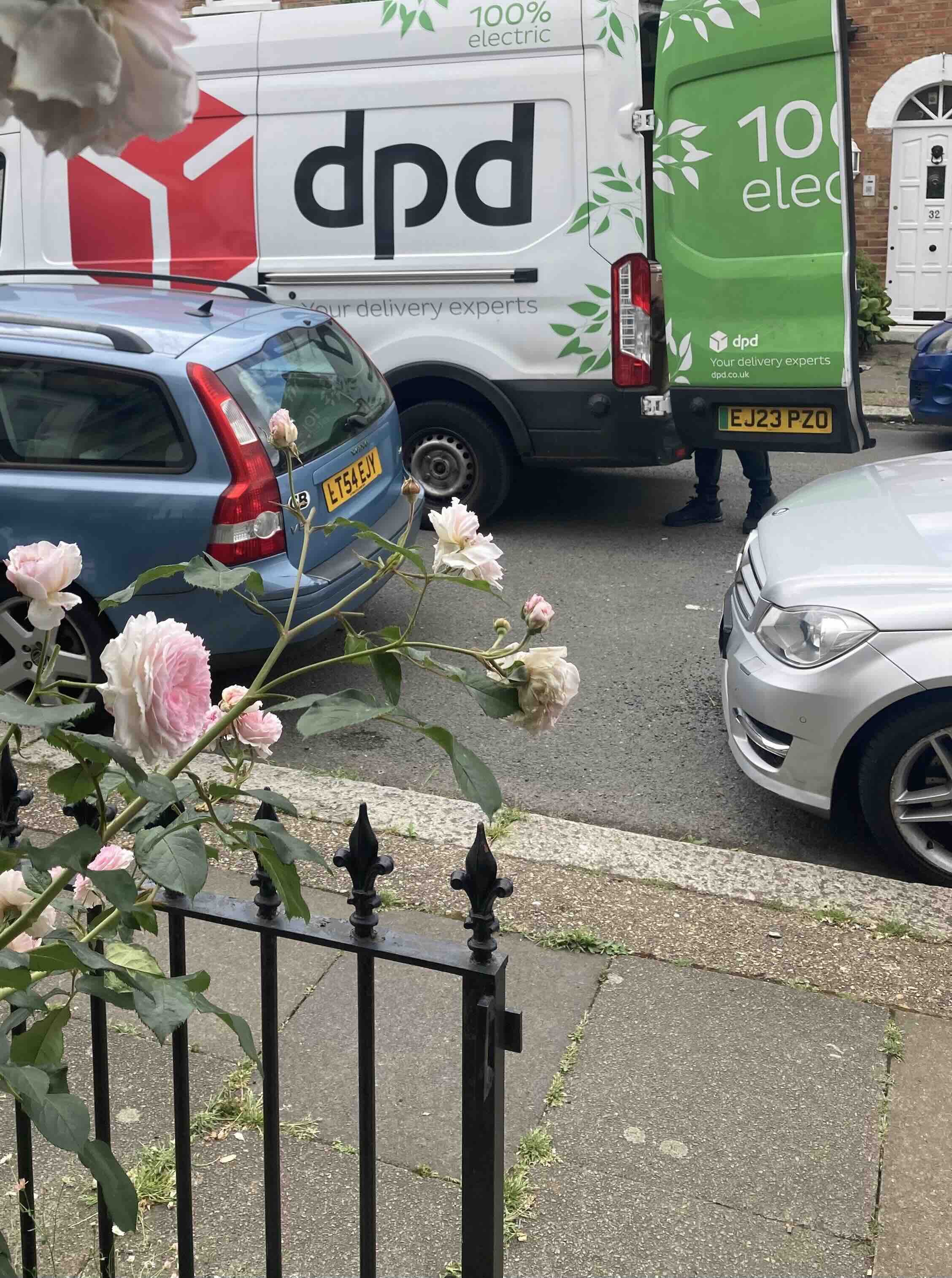 Photograph from the doorstep of terraced house in London, showing a DPD delivery van in the middle of the street, with doors open.