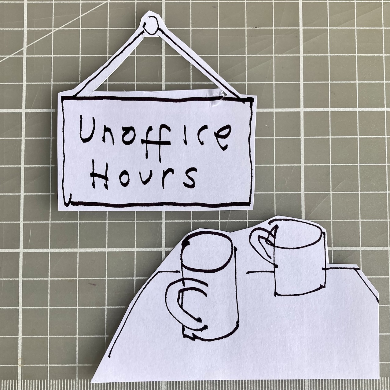 Photo of a bits of paper on a cutting board, one featuring an illustration of a sign reading 'Unoffice Hours', the other showing two mugs on a table.
