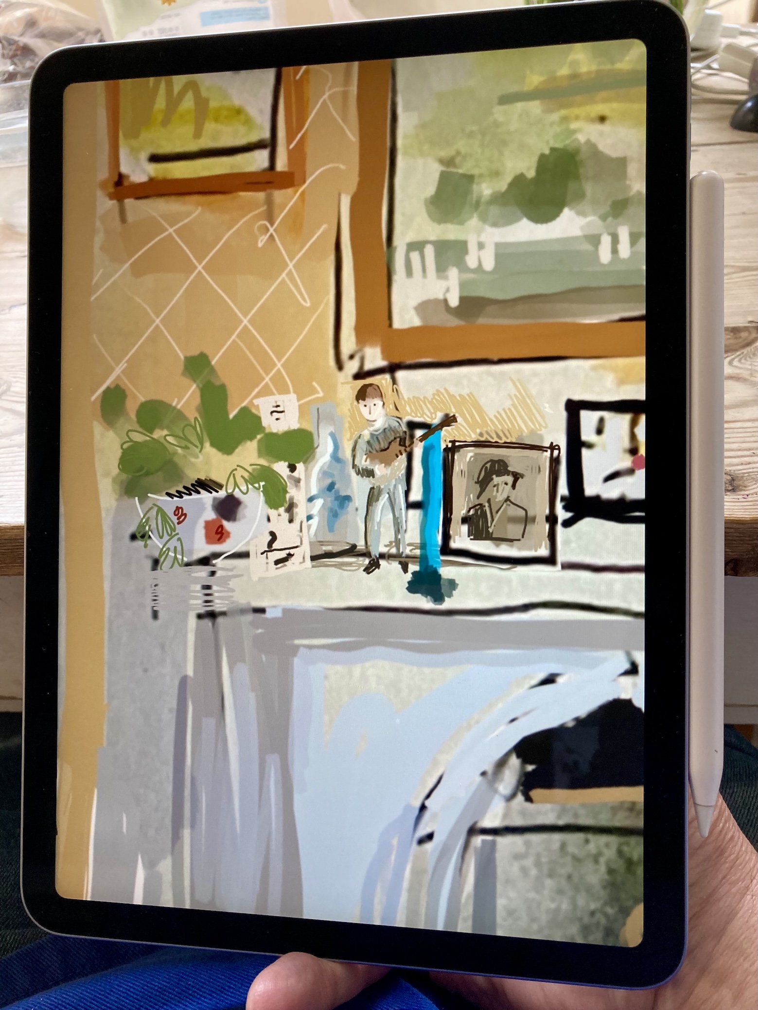 A hand holding an iPad with an Apple Pencil, the screen showing an in-progress digital drawing of a mantelpiece: a plant in a pot, framed pictures on the wall behind, a small ceramic Beatle figure standing on the mantel.