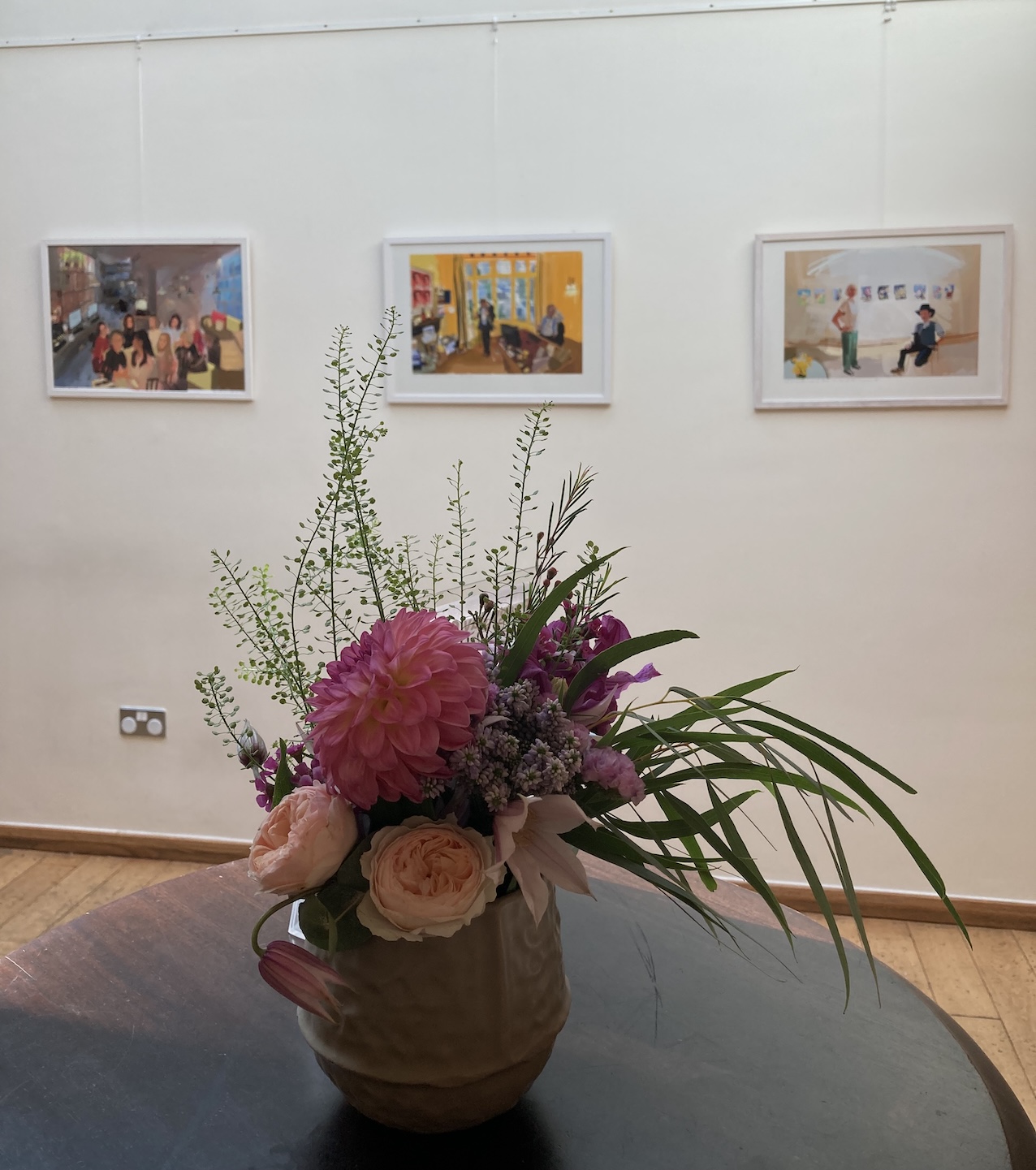 Three portraits on the wall, with flowers in the foreground.