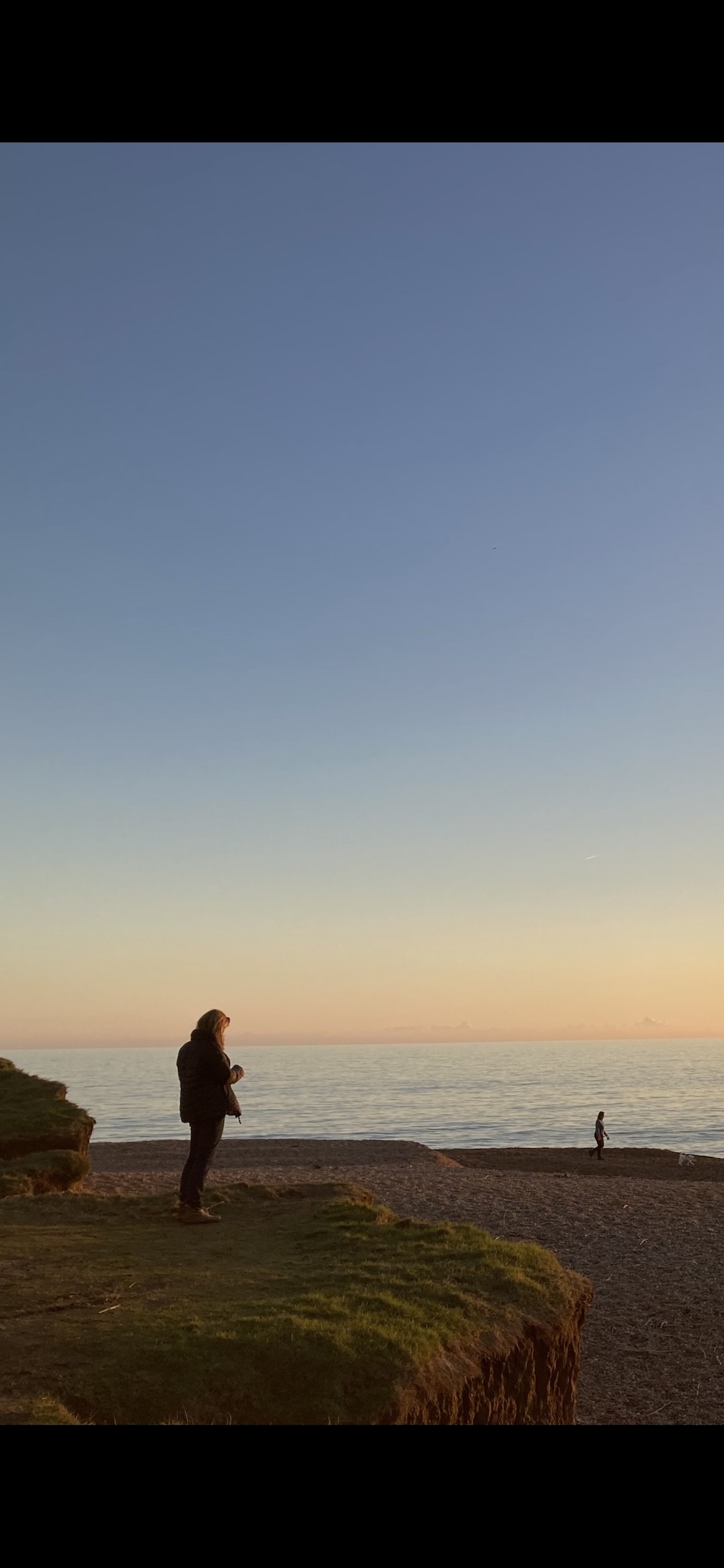 The left portion of the same scene as a tall screenshot - the figure on the cliff, the beach and the sea The left portion of the same scene as a tall screenshot - the figure on the cliff, the beach and the sea