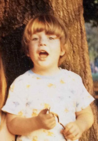 boy aged 4 or 5, in golden afternoon sunshine, looking as if he's speaking with animation to the photographer