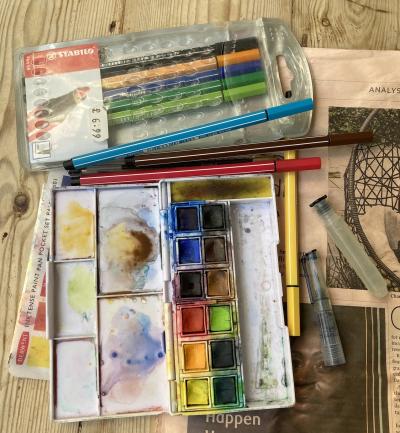 Pens and paints on a table with a copy of the Financial Times
